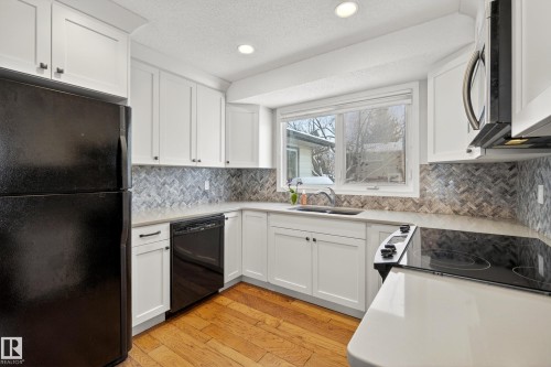The kitchen features white cabinetry, black appliances, light-colored countertops, and a tile backsplash - 17 Austin Crescent, St. Albert, AB - Indoor Photo Showing Kitchen