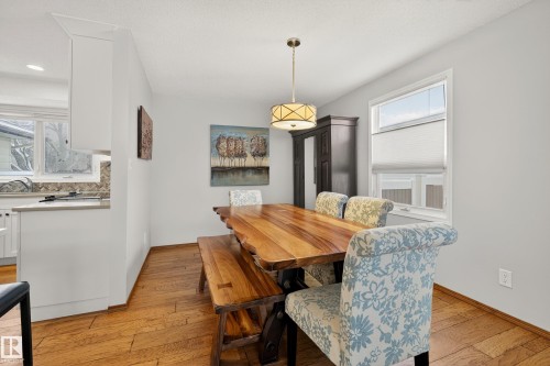 Dining area featuring hardwood floors, a large window with blinds, and a modern light fixture - 17 Austin Crescent, St. Albert, AB - Indoor Photo Showing Dining Room