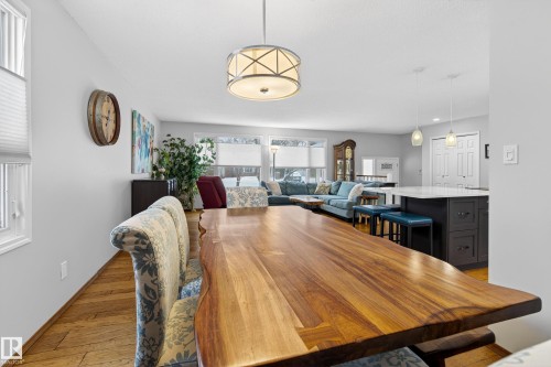 Open-concept dining and living area featuring hardwood flooring, a statement chandelier, and an island with seating - 17 Austin Crescent, St. Albert, AB - Indoor Photo Showing Dining Room