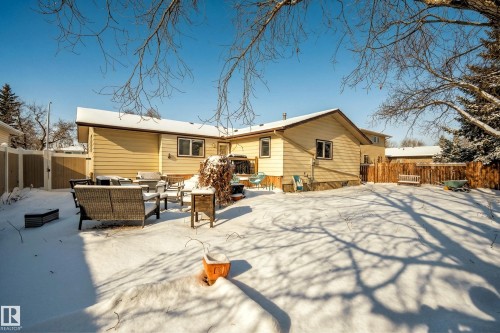 The property features a spacious backyard with a large patio area and a wooden fence - 17 Austin Crescent, St. Albert, AB - Outdoor With Deck Patio Veranda