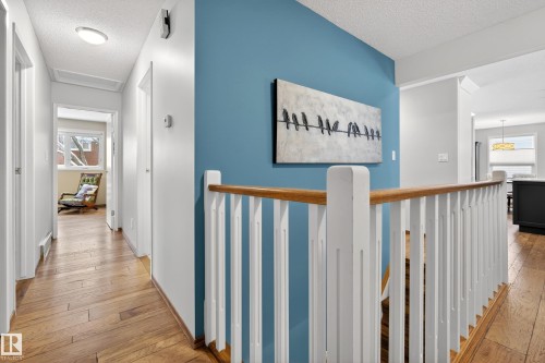 This property features hardwood flooring and a staircase with a wooden handrail and white balusters - 17 Austin Crescent, St. Albert, AB - Indoor Photo Showing Other Room