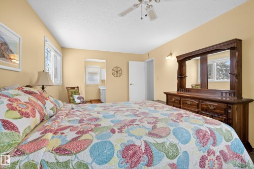 This bedroom features painted walls, a textured ceiling, a ceiling fan with lighting, and a window providing natural light - 17 Austin Crescent, St. Albert, AB - Indoor Photo Showing Bedroom