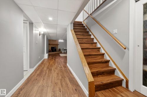 Hallway featuring wood flooring, neutral grey walls, and white trim, with a staircase featuring wooden steps and handrails - 17 Austin Crescent, St. Albert, AB - Indoor Photo Showing Other Room