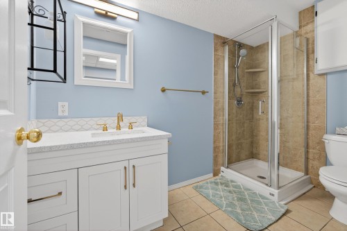 Bathroom featuring a white vanity with gold-toned fixtures, a glass-enclosed shower, and tiled flooring - 17 Austin Crescent, St. Albert, AB - Indoor Photo Showing Bathroom