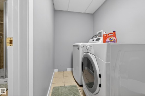 Dedicated laundry area featuring a front-loading washing machine and a dryer, with light-colored tile flooring - 17 Austin Crescent, St. Albert, AB - Indoor Photo Showing Laundry Room