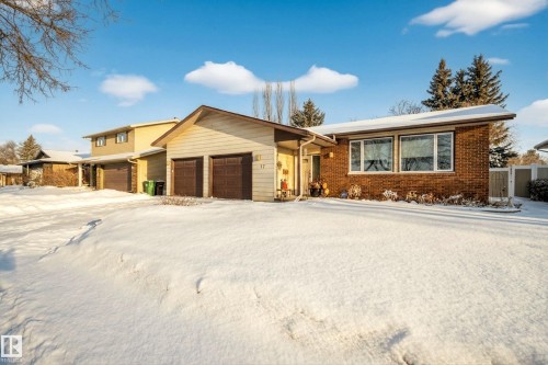 The property features a brick exterior with large windows, an attached two-car garage, and a snow-covered front yard - 17 Austin Crescent, St. Albert, AB - Outdoor