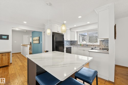 The kitchen features white cabinetry, a large window, and a white and gray veined countertop on the island - 17 Austin Crescent, St. Albert, AB - Indoor