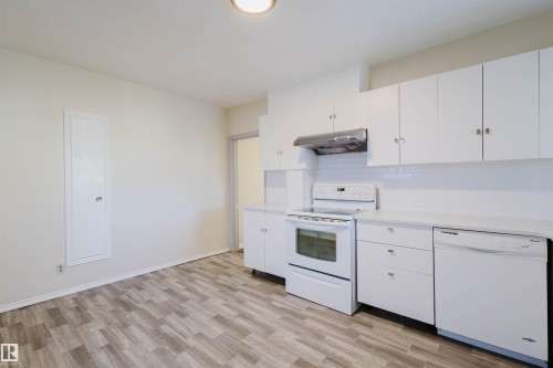 Bright kitchen featuring white cabinetry, a subway tile backsplash, white appliances, and wood-finish flooring - 10511 80 Street, Edmonton, AB - Indoor Photo Showing Kitchen