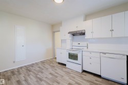 Bright kitchen featuring white cabinetry, a subway tile backsplash, white appliances, and wood-finish flooring - 