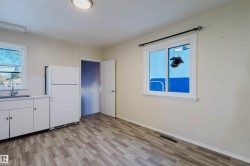 Kitchen area featuring wood-finish flooring, white cabinetry, and a white refrigerator - 