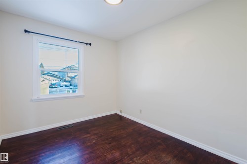 Room featuring wood-finish flooring, white baseboards, a single window with white trim, and a ceiling-mounted light fixture - 10511 80 Street, Edmonton, AB - Indoor Photo Showing Other Room