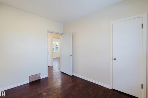 Spacious room featuring dark wood-finish flooring, light-toned wall paint, and white baseboards - 10511 80 Street, Edmonton, AB - Indoor Photo Showing Other Room
