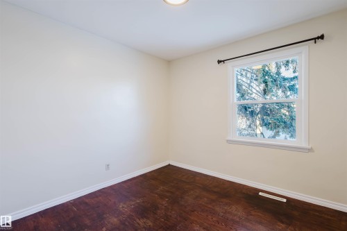Bright room featuring a single window, wood-finish flooring, light-toned walls, white baseboards, and a ceiling-mounted light fixture - 10511 80 Street, Edmonton, AB - Indoor Photo Showing Other Room