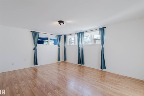 Hardwood-style flooring throughout a room with white walls and multiple windows - 10511 80 Street, Edmonton, AB - Indoor Photo Showing Other Room