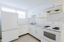Bright kitchen featuring white cabinetry, light-toned countertops, a white range, and a white refrigerator - 