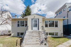 Exterior featuring light yellow siding, multiple windows, and a prominent front entrance with a storm door - 