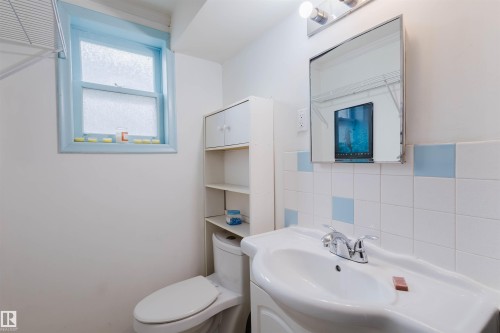 Bathroom featuring a wall-mounted sink, ceramic tile backsplash with accent squares, and a medicine cabinet with integrated lighting - 10511 80 Street, Edmonton, AB - Indoor Photo Showing Bathroom