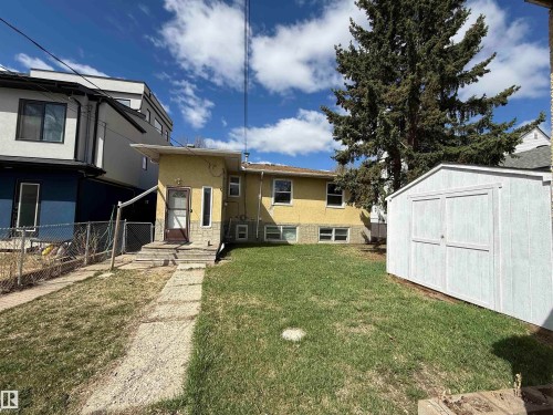 Expansive rear yard featuring a grass lawn, paved pathway, and a detached storage shed - 10511 80 Street, Edmonton, AB - Outdoor
