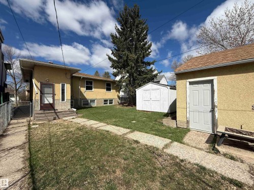 Rear exterior featuring a stucco finish, multiple windows, and a separate storage shed - 10511 80 Street, Edmonton, AB - Outdoor