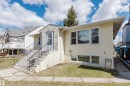 Yellow siding exterior with white trim, featuring multiple windows and a front entrance with a screen door and wrought iron railings - 10511 80 Street, Edmonton, AB  - Outdoor 