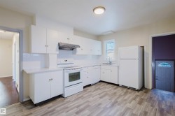 Bright kitchen featuring white cabinetry, white subway tile backsplash, and wood-finish flooring - 