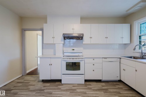 Kitchen featuring white cabinetry, white subway tile backsplash, white appliances, and wood-finish flooring - 10511 80 Street, Edmonton, AB - Indoor Photo Showing Kitchen