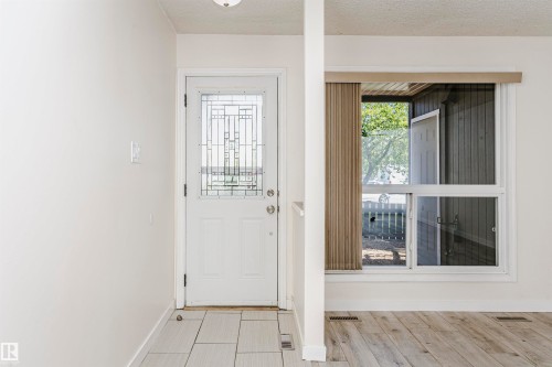 Entryway featuring a white door with decorative glass inserts, light gray tile flooring, and a large window with white framing - 9221 172 Street, Edmonton, AB - Indoor Photo Showing Other Room