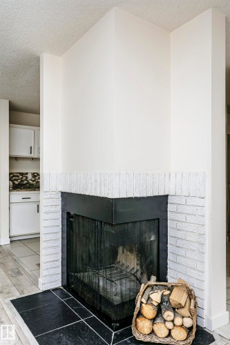 Corner fireplace with painted brick surround and black hearth - 9221 172 Street, Edmonton, AB - Indoor Photo Showing Living Room With Fireplace