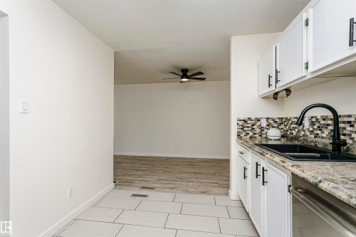 Kitchen featuring white cabinetry with matte black hardware, a black sink with a matte black faucet, and a mosaic tile backsplash - 9221 172 Street, Edmonton, AB - Indoor Photo Showing Kitchen With Double Sink