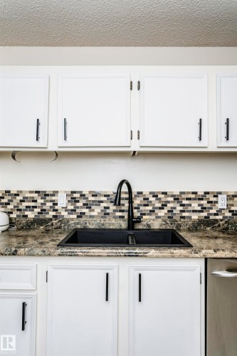 Kitchen sink area featuring a black composite sink, a black gooseneck faucet, and a mosaic tile backsplash - 9221 172 Street, Edmonton, AB - Indoor Photo Showing Kitchen With Upgraded Kitchen