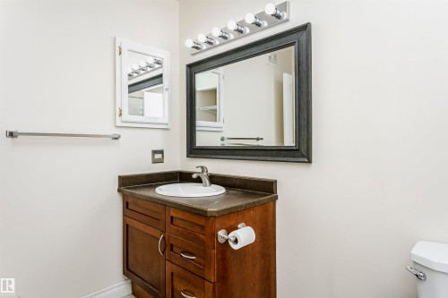 Bathroom vanity featuring a dark wood-finish cabinet with a white basin and chrome faucet, under a dark framed mirror - 9221 172 Street, Edmonton, AB - Indoor Photo Showing Bathroom