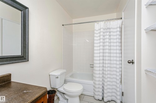 Bathroom featuring a white bathtub, ceramic tile shower surround, and a vanity with a dark countertop - 9221 172 Street, Edmonton, AB - Indoor Photo Showing Bathroom