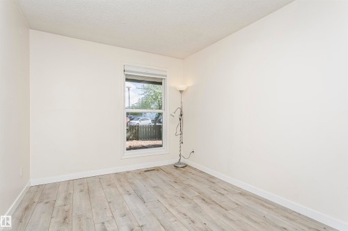 Bright interior space featuring a window with white trim, light-toned wood-finish flooring, white baseboards, and neutral wall tones - 9221 172 Street, Edmonton, AB - Indoor Photo Showing Other Room
