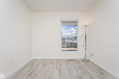 Bright room featuring light wood-finish flooring, white baseboards, and a single window with blinds - 9221 172 Street, Edmonton, AB - Indoor Photo Showing Other Room