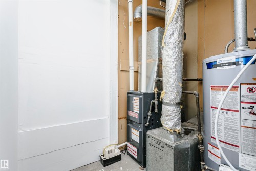 Utility area featuring a water heater and furnace with exposed ductwork and piping - 9221 172 Street, Edmonton, AB - Indoor Photo Showing Basement