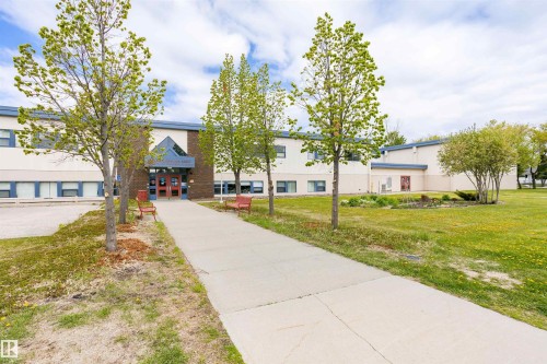 Expansive institutional building with a prominent main entrance featuring double doors and an overhead architectural element - 9221 172 Street, Edmonton, AB - Outdoor With Facade