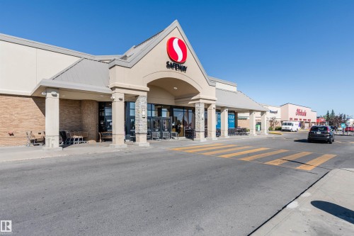 Commercial retail storefront featuring a prominent arched entryway, stone-clad columns, and a metal-clad roofline - 9221 172 Street, Edmonton, AB - Outdoor