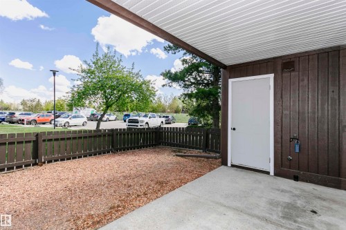 Covered patio area with concrete flooring, framed by dark wood-paneled walls and a matching privacy fence - 9221 172 Street, Edmonton, AB - Outdoor With Exterior