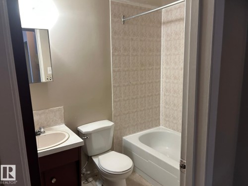 Bathroom featuring a tiled shower and bathtub combination, a vanity with a sink, and a toilet - 4 10164 150 Street, Edmonton, AB - Indoor Photo Showing Bathroom