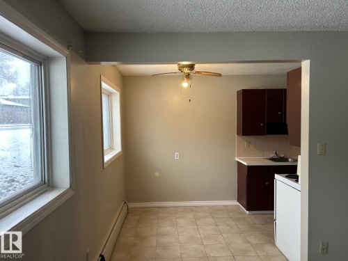 Kitchen and dining area featuring tiled flooring, a ceiling fan, and two windows providing natural light - 4 10164 150 Street, Edmonton, AB - Indoor