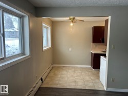 This property features a dining area with tiled flooring, a ceiling fan, and two windows providing natural light - 