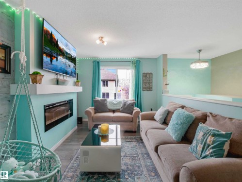 Living area featuring a modern linear fireplace with a mantle, light-colored walls, and wood-finish flooring - 44 1140 Chappelle Boulevard, Edmonton, AB - Indoor Photo Showing Living Room With Fireplace