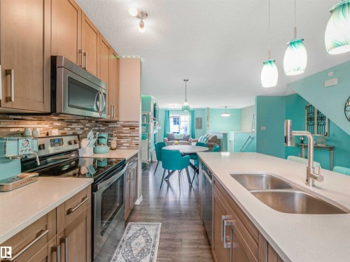 Modern kitchen featuring wood-finish cabinetry, stainless steel appliances, and a mosaic tile backsplash - 44 1140 Chappelle Boulevard, Edmonton, AB - Indoor Photo Showing Kitchen With Double Sink