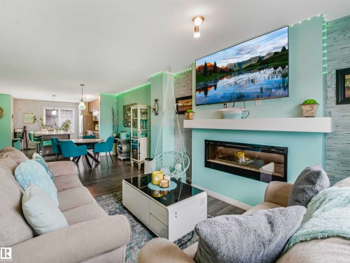 Living area featuring a sleek fireplace with a white mantel, dark wood-finish flooring, and recessed ceiling lighting - 44 1140 Chappelle Boulevard, Edmonton, AB - Indoor Photo Showing Living Room With Fireplace
