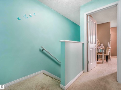 Carpeted staircase with white handrail and baseboards - 44 1140 Chappelle Boulevard, Edmonton, AB - Indoor Photo Showing Other Room