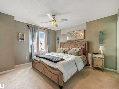 Carpeted bedroom featuring a window with natural light, a ceiling fan with integrated lighting, and a textured accent wall - 44 1140 Chappelle Boulevard, Edmonton, AB - Indoor Photo Showing Bedroom