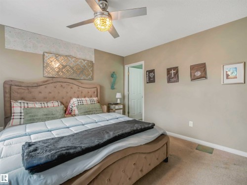 Carpeted room featuring a ceiling fan with integrated lighting, neutral wall paint, and a white door frame - 44 1140 Chappelle Boulevard, Edmonton, AB - Indoor Photo Showing Bedroom