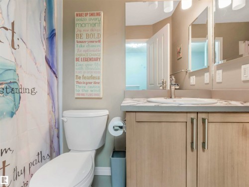 Bathroom vanity featuring a vessel sink, single-handle faucet, and light wood-finish cabinetry with brushed nickel pulls - 44 1140 Chappelle Boulevard, Edmonton, AB - Indoor Photo Showing Bathroom