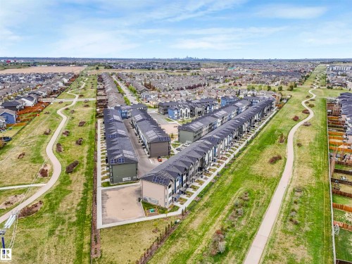 Aerial perspective showcasing a residential development with rows of townhomes featuring dark shingle roofs and integrated solar panels - 44 1140 Chappelle Boulevard, Edmonton, AB - Outdoor With View