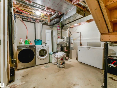 Dedicated laundry area featuring exposed overhead utilities, concrete flooring, and a visible water heater - 44 1140 Chappelle Boulevard, Edmonton, AB - Indoor Photo Showing Laundry Room